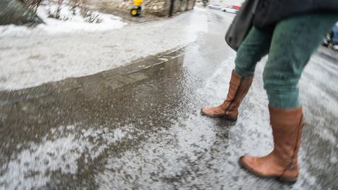 Eine Frau geht bei Glatteis über eine Straße
