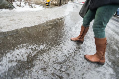 Eine Frau geht bei Glatteis über eine Straße