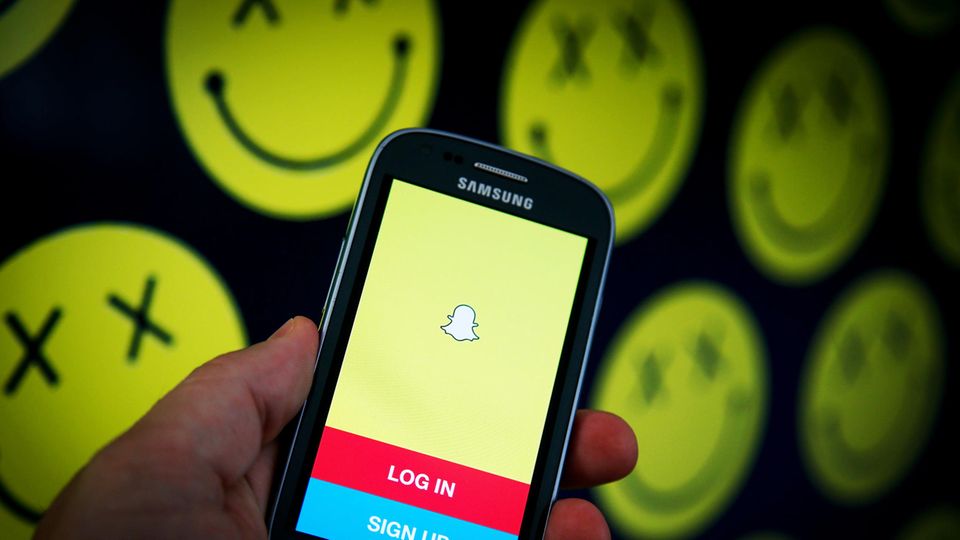 Die App Snapchat ist auf einem Samsung-Smartphone geöffnet, im Hintergrund sind morbide Smilys zu sehen
