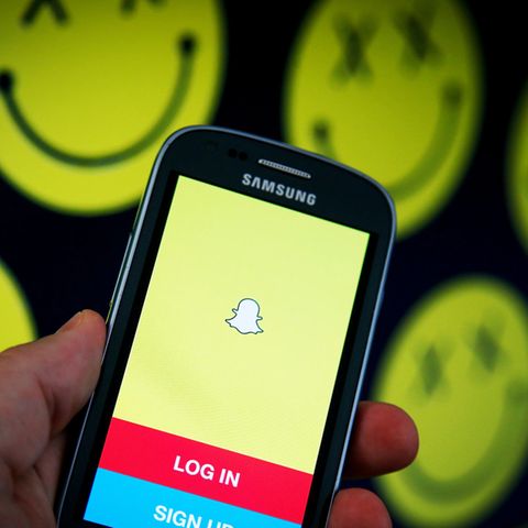 Die App Snapchat ist auf einem Samsung-Smartphone geöffnet, im Hintergrund sind morbide Smilys zu sehen