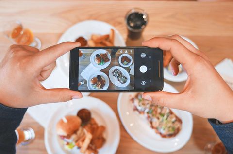 Jemand fotografiert mit seinem Handy sein Essen