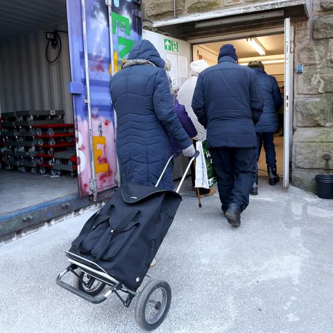 Kunden der Essener Tafel gehen mit ihren Einkaufswagen zur Lebensmittelausgabestelle.