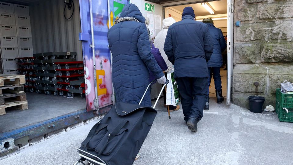 Kunden der Essener Tafel gehen mit ihren Einkaufswagen zur Lebensmittelausgabestelle.