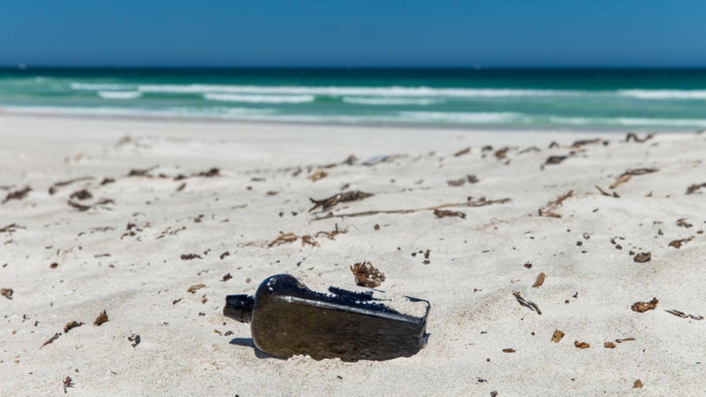 Eine Flasche liegt im Sand eines Strandes - Es soll sich um die deutsche Flaschenpost handeln, die nach 132 Jahren in Australien