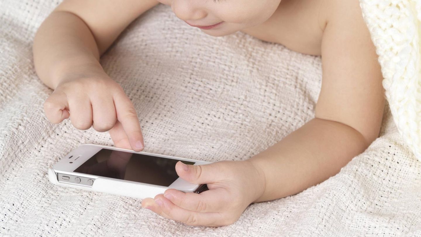 Ein Kleinkind tipp auf ein iPhone