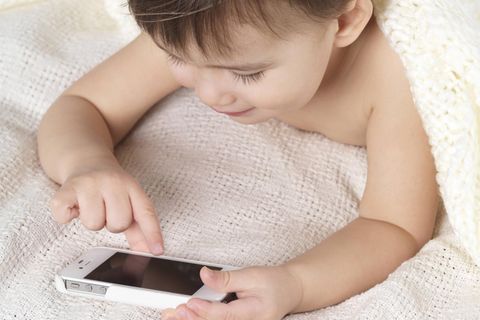 Ein Kleinkind tipp auf ein iPhone