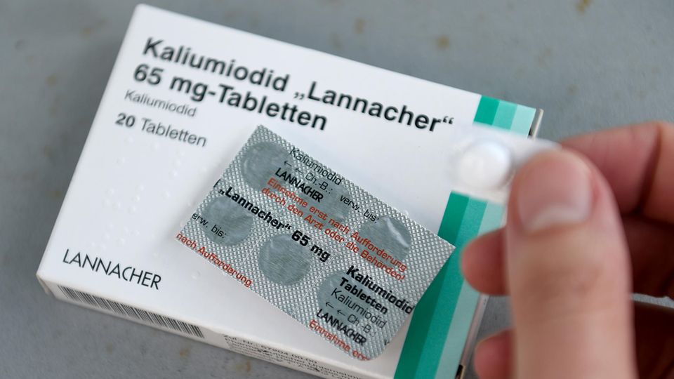 Auf einer weißen Schachtel mit dünnem grünen Rand liegt ein Blister mit sechs Jodtabletten