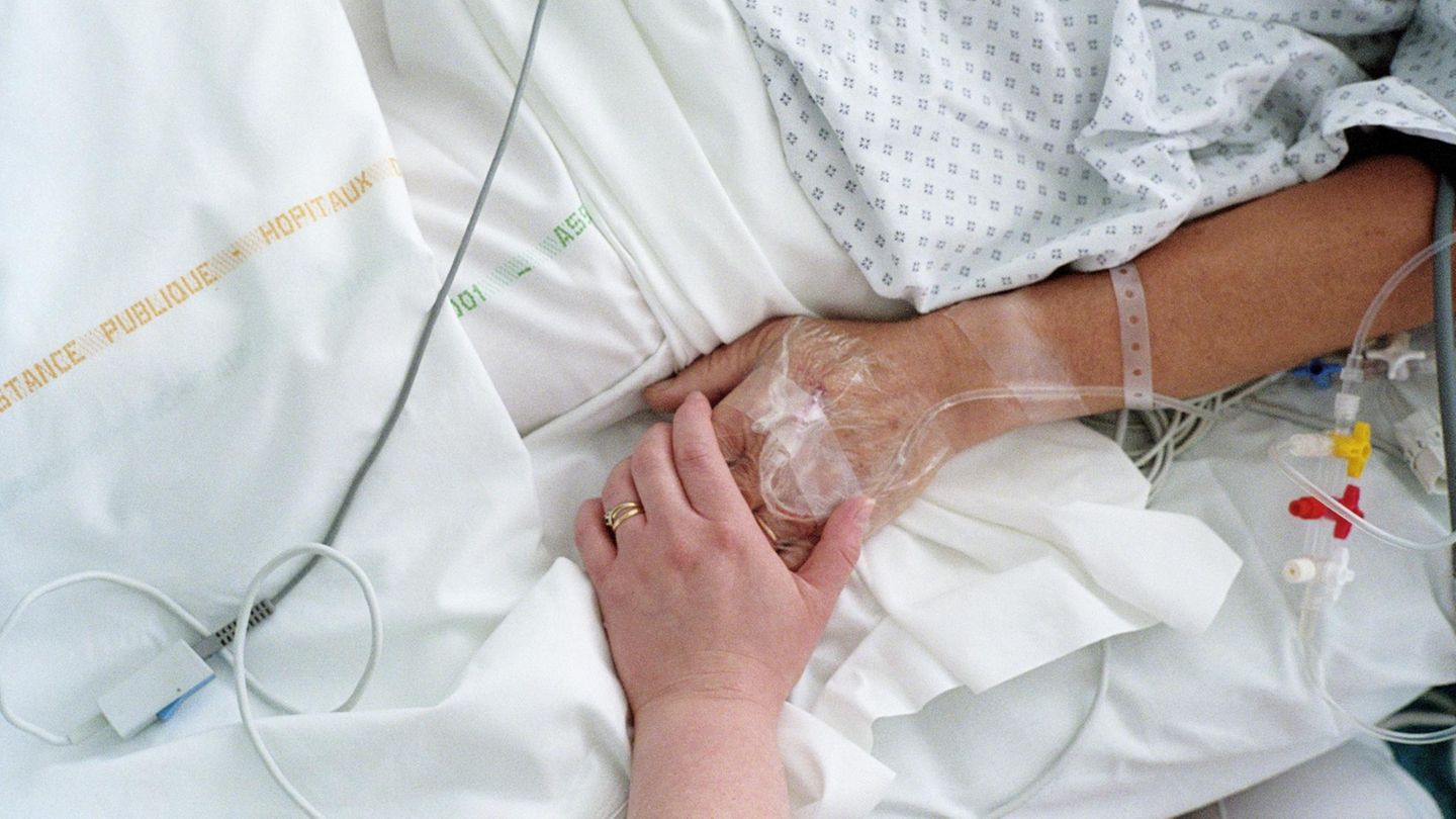 Eine Krankenschwester hält die Hand eines Patienten.