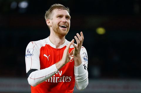 Per Mertesacker steht im rot-weißen Arsenal-Trikot nach Abpfiff auf dem Rasen, lächelt und applaudiert.