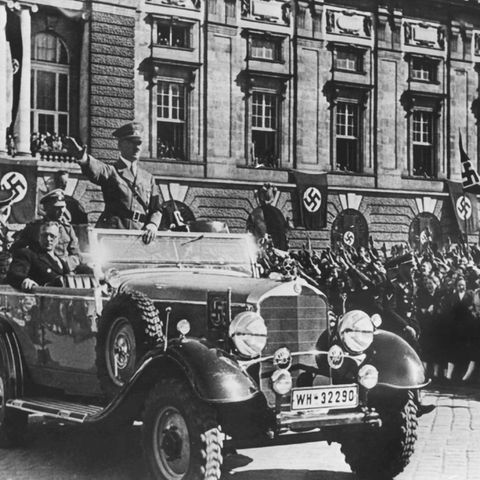 Am 14. März 1938 jubeln Österreicher in Wien Adolf Hitler zu. Neben ihm sitzt der österreichische Kanzler Arthur Seyss-Inquart im Parade-Wagen.