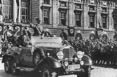 Am 14. März 1938 jubeln Österreicher in Wien Adolf Hitler zu. Neben ihm sitzt der österreichische Kanzler Arthur Seyss-Inquart im Parade-Wagen.