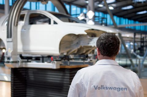 Ein VW-Mitarbeiter steht vor einem unfertigen VW-Auto