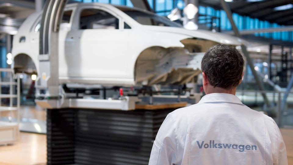 Ein VW-Mitarbeiter steht vor einem unfertigen VW-Auto