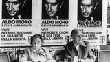 Ein Paar sitzt unter Plakaten mit dem Porträt des ermordeten Aldo Moro
