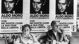 Ein Paar sitzt unter Plakaten mit dem Porträt des ermordeten Aldo Moro