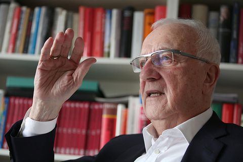 Während Fritz Pleitgen spricht, sitzt er vor einem Bücherregal, dessen Inhalt von seinem Reporterleben zeugt.