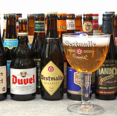 Ein Bierglas steht vor unterschiedlichen Biersorten aus Belgien