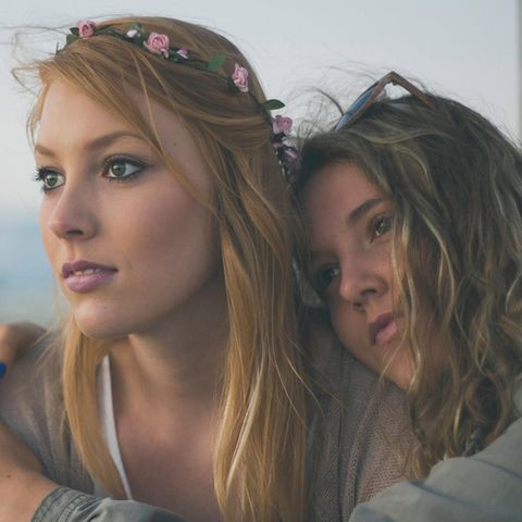 Millennials: Zwei junge Mädchen mit Blumen in den Haaren umarmen sich