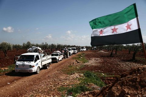 Auf einem Feldweg rollt eine Kolonne aus Autos, Transportern und Traktoren aus der umkämpften Stadt Afrin heraus