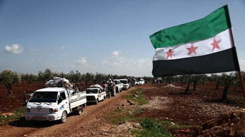 Auf einem Feldweg rollt eine Kolonne aus Autos, Transportern und Traktoren aus der umkämpften Stadt Afrin heraus