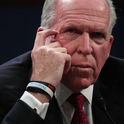 John O. Brennan, ein grauhaariger Mann in dunkelblauem Anzug und mit roter Krawatte, kratzt mit dem Finger seinen Augenwinkel