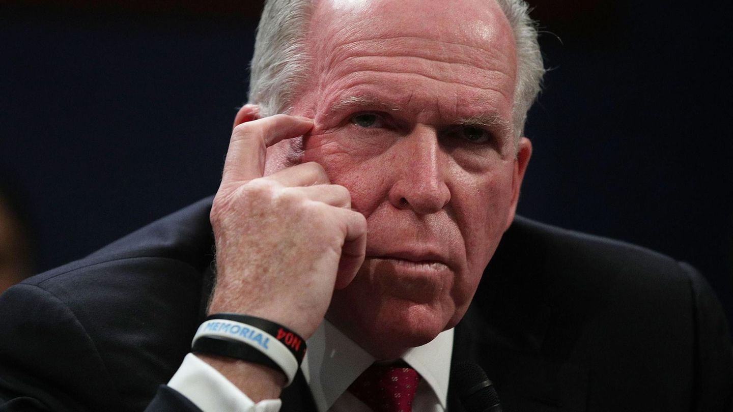 John O. Brennan, ein grauhaariger Mann in dunkelblauem Anzug und mit roter Krawatte, kratzt mit dem Finger seinen Augenwinkel
