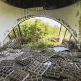 Die Deckenverkleidung liegt auf dem Fußboden, durch das Panoramafenster fällt das Grün in dieses Gebäude ein.