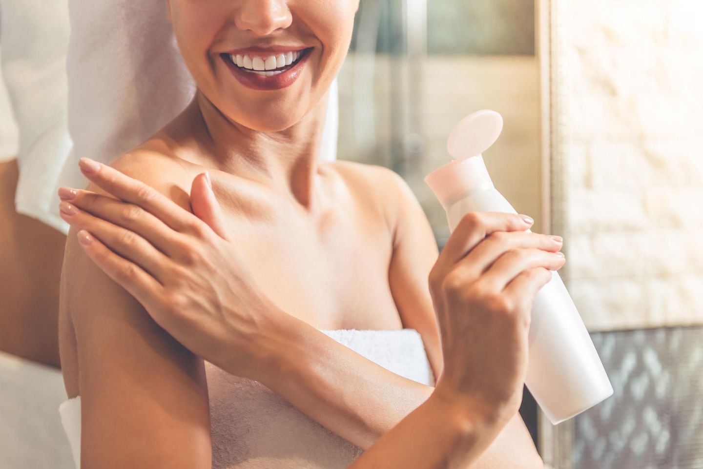Eine Frau cremt sich mit einer Körperlotion ein