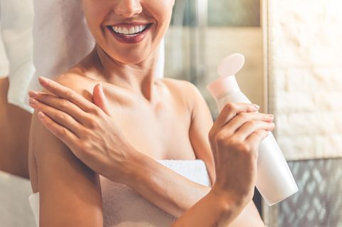Eine Frau cremt sich mit einer Körperlotion ein