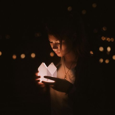 Eine junge Frau schaut in ein Kerzenlicht