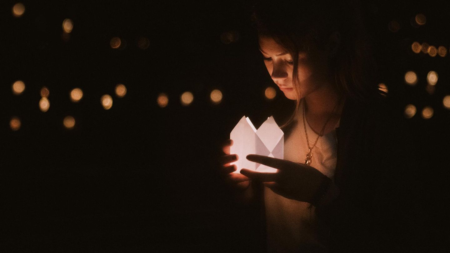 Eine junge Frau schaut in ein Kerzenlicht