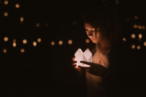 Eine junge Frau schaut in ein Kerzenlicht