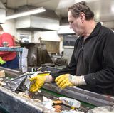 In einem abgeschotteten Bereich, jenseits von Staub und Lärm im Rest der Halle, kontrollieren sieben Alba-Mitarbeiter, ob die Sortierung geklappt hat. Bloß der süßlich-schwere Geruch ist der Gleiche. Was hier falsch ankommt, wird manuell aussortiert und mit traumwandlerischer Sicherheit und ohne zu gucken in den richtigen "Wertstoffstrom" geworfen. Denn ganz ohne menschliche Hilfe schafft es die Technik nicht, den Wohlstandsmüll von Millionen zu trennen.