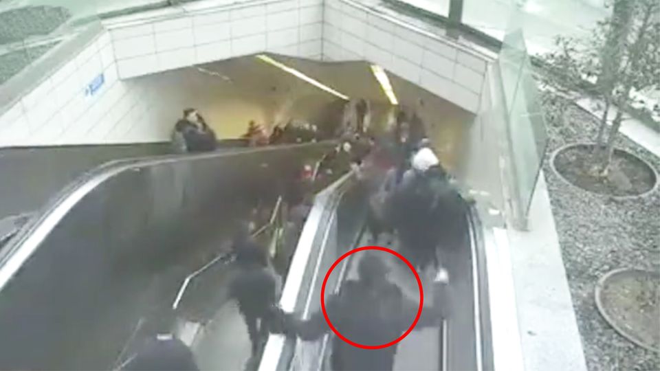 Ein Mann strauchelt und greift noch an die Handläufe der Rolltreppe