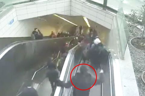 Ein Mann strauchelt und greift noch an die Handläufe der Rolltreppe