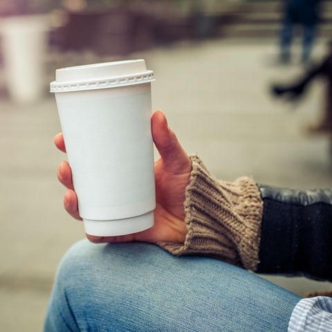 Eine Frau hält einen Pappbecher in der Hand