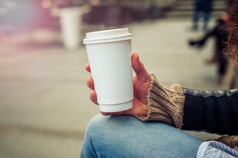 Eine Frau hält einen Pappbecher in der Hand