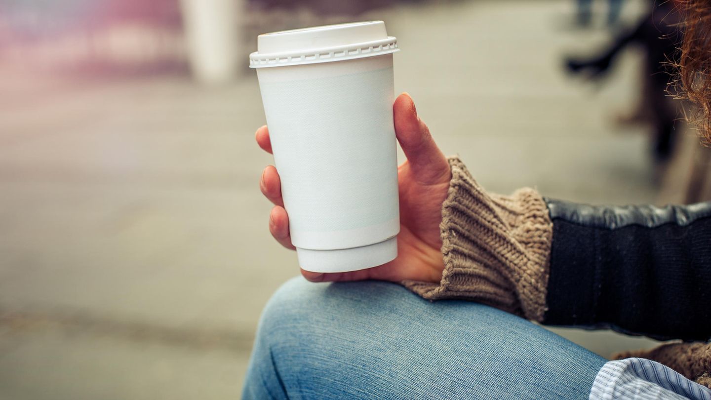 Eine Frau hält einen Pappbecher in der Hand