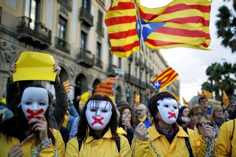 Proteste in Barcelona: Demonstranten mit Masken und verketteten Händen nehmen an einer Demonstration vor hochgehaltenen Esteladas, der Unabhängigkeitsflagge Kataloniens, teil. 