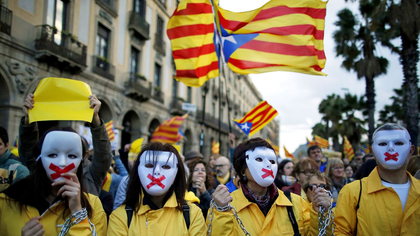 Proteste in Barcelona: Demonstranten mit Masken und verketteten Händen nehmen an einer Demonstration vor hochgehaltenen Esteladas, der Unabhängigkeitsflagge Kataloniens, teil. 
