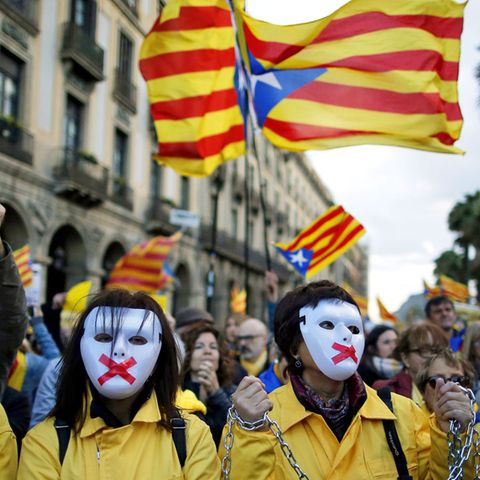 Proteste in Barcelona: Demonstranten mit Masken und verketteten Händen nehmen an einer Demonstration vor hochgehaltenen Esteladas, der Unabhängigkeitsflagge Kataloniens, teil. 