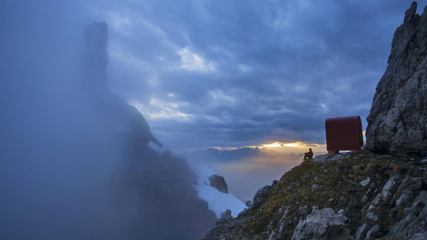 Schutzraum in großer Landschaft – ein Bergsteiger blickt vor dem Bivacco Ugo Dalla Bernardina in der Schiara-Gruppe hinüber zur Turmgestalt der Gusela.
