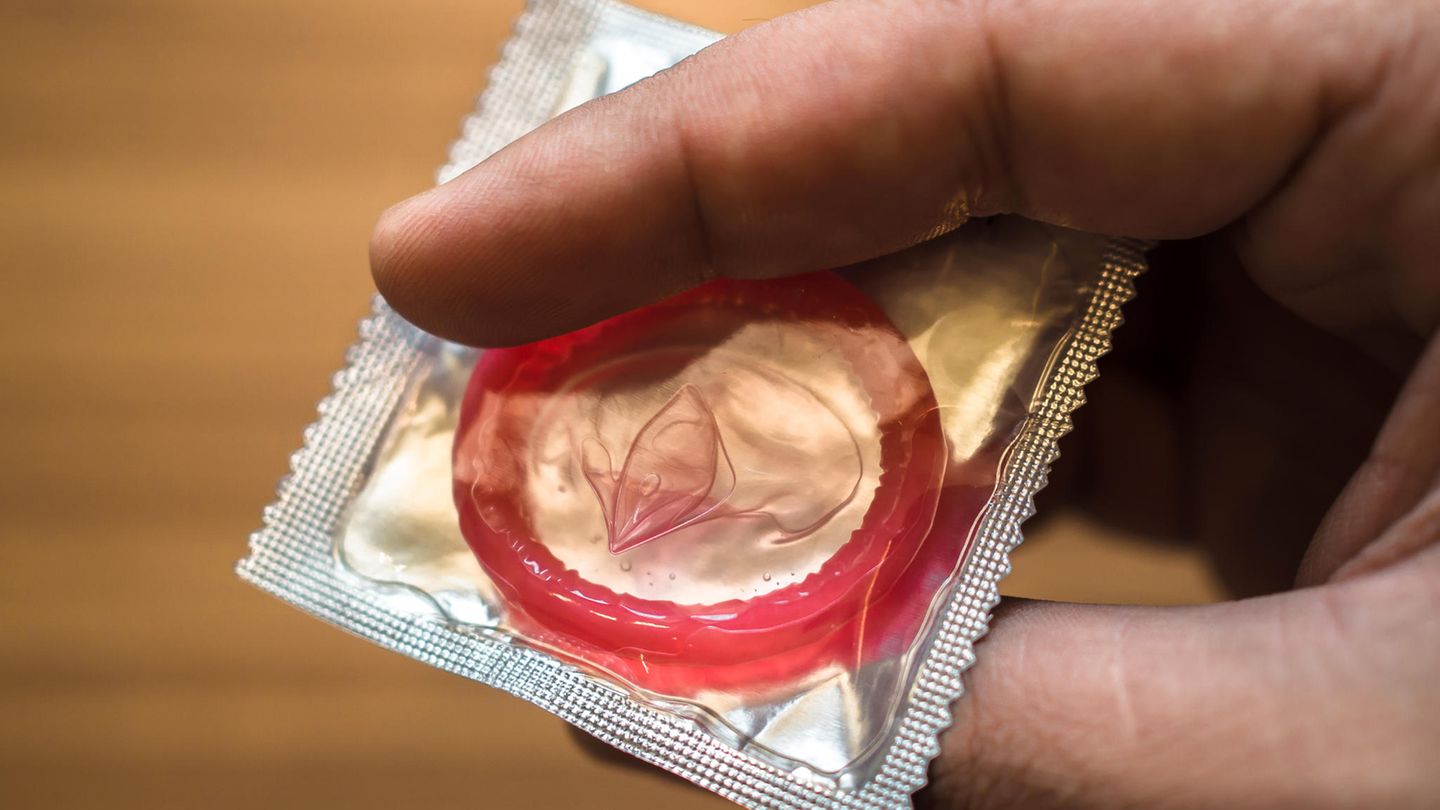 Ein Mann hält ein Kondom in der Hand