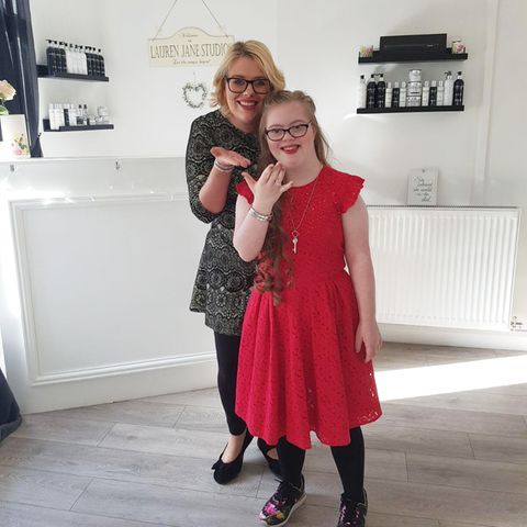 Ein Mädchen in rotem Kleid und mit Brille und ihre Mutter werfen Kusshände