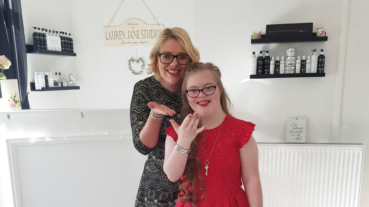 Ein Mädchen in rotem Kleid und mit Brille und ihre Mutter werfen Kusshände