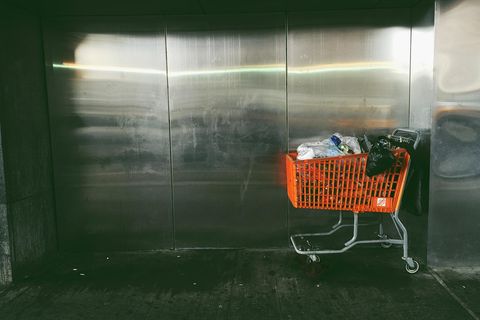 Oranger Einkaufswagen mit Müll gefüllt