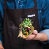 Anstelle eines Würstchens sind im Hot-Dog-Brötchen getrocknete und glacierte Baby-Möhren, Bete- und Beeren-Ketchup, Senf, Kurkuma-Creme, geröstete Zwiebeln, Gurkensalat und ein Kräuter-Salat-Mix. 