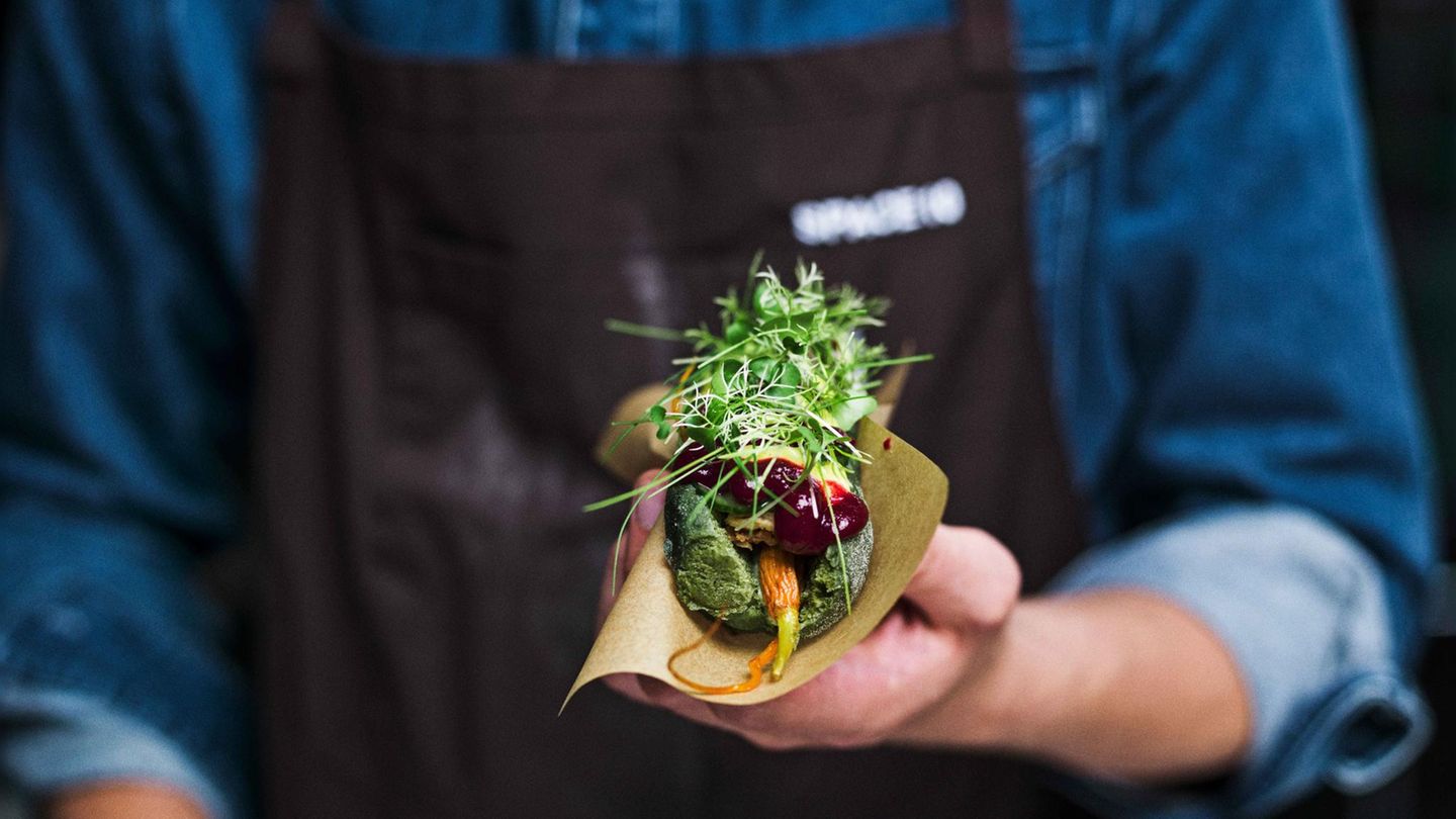 Anstelle eines Würstchens sind im Hot-Dog-Brötchen getrocknete und glacierte Baby-Möhren, Bete- und Beeren-Ketchup, Senf, Kurkuma-Creme, geröstete Zwiebeln, Gurkensalat und ein Kräuter-Salat-Mix. 