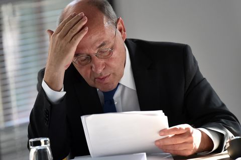 Gregor Gysi sitzt an einem Tisch und blättert in Papieren