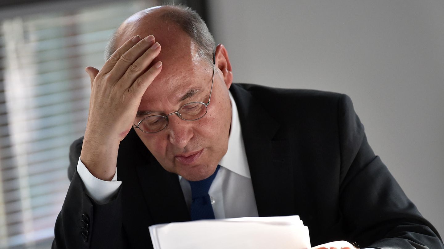 Gregor Gysi sitzt an einem Tisch und blättert in Papieren